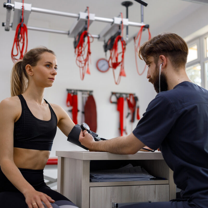 Physiotherapist doctor measures blood pressure of a young athletic woman